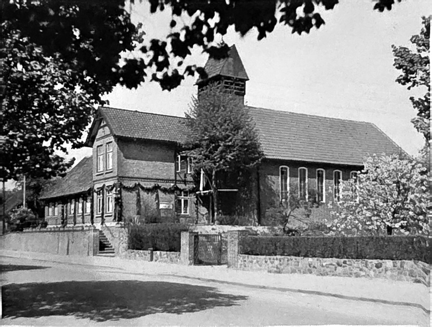Die erste Kirche Heilig Kreuz mit dem Pfarrhaus, festlich geschmückt