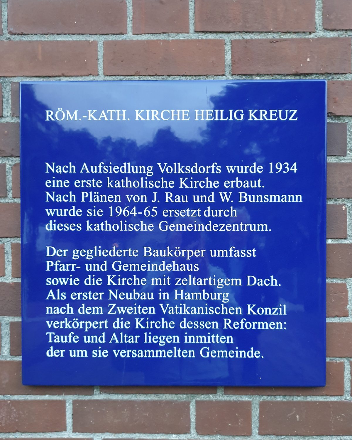 Blaue Denkmalschutztafel an der Backsteinwand der Kirche