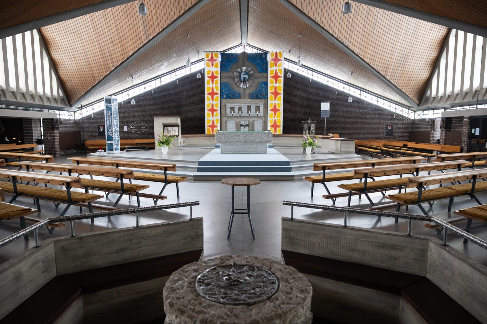 Blick vom Taufbecken über die Bänke zum Altar