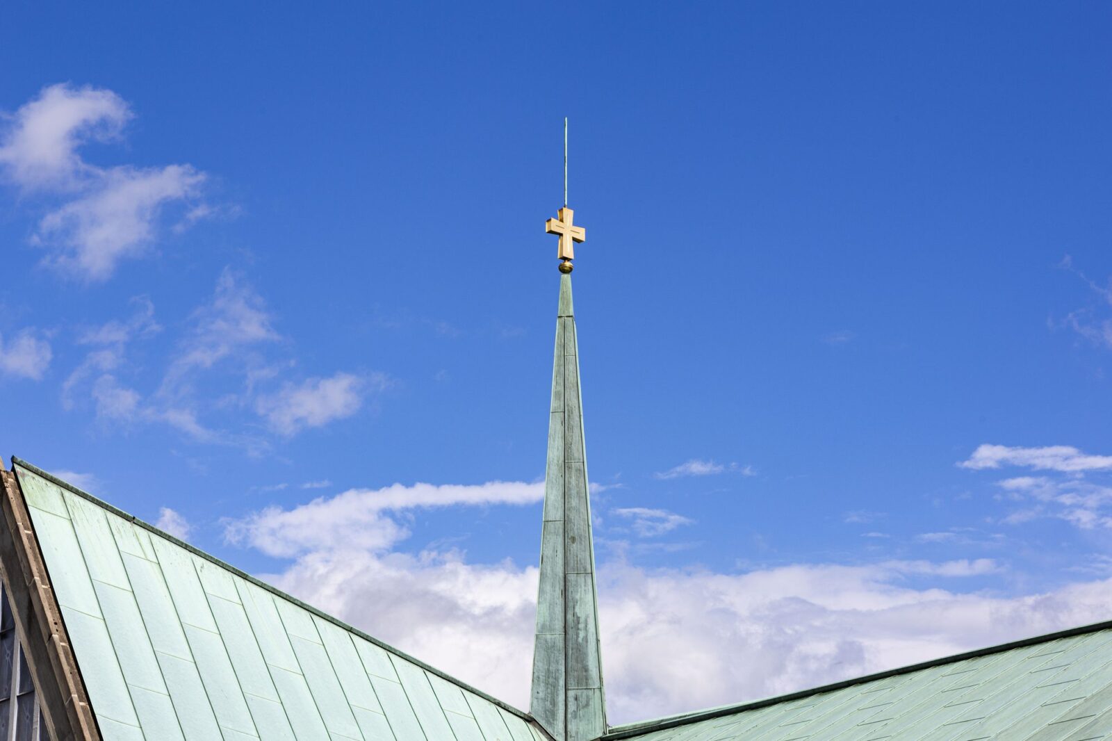 Die Turmspitze mit Kreuz vor blauem Himmel