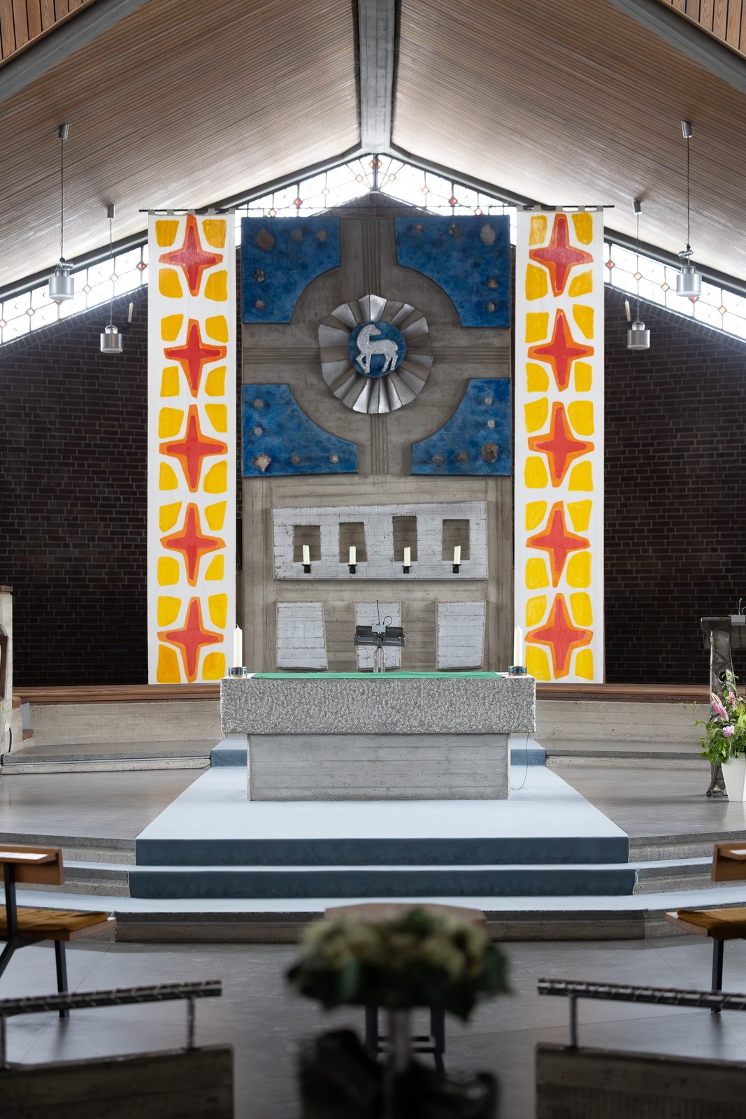 Blick durch den Kirchenraum auf den Altar und die farbige Stele